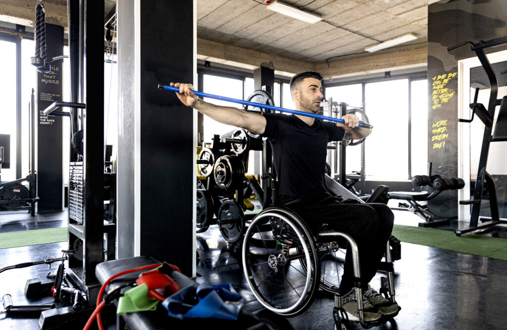 Middle-aged man in a wheelchair exercising in the gym stock photo