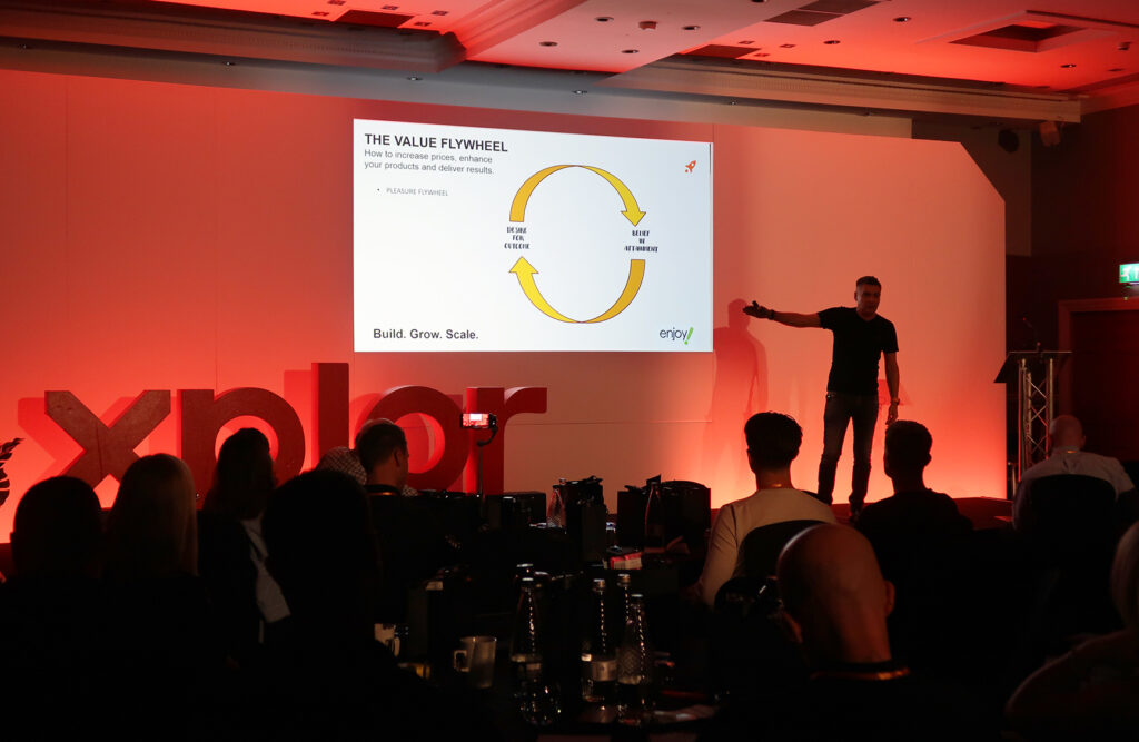 A photo of Adrian Marks, Founder & CEO of customer acquisition agency enjoy!, on stage at the Xplor Xperience in May 2024 at The Park Royal Hotel in Cheshire, UK.