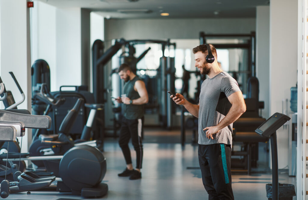 A photo of a man in the gym looking at his phone happily about to start his workout