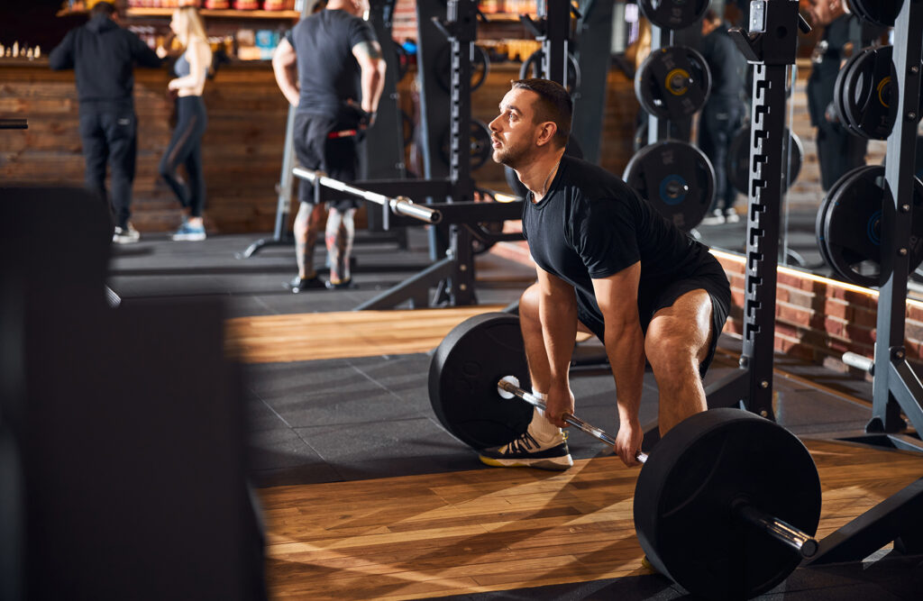 A photo of a man getting value for his gym membership investment lifting a heavy barbell in the gym 