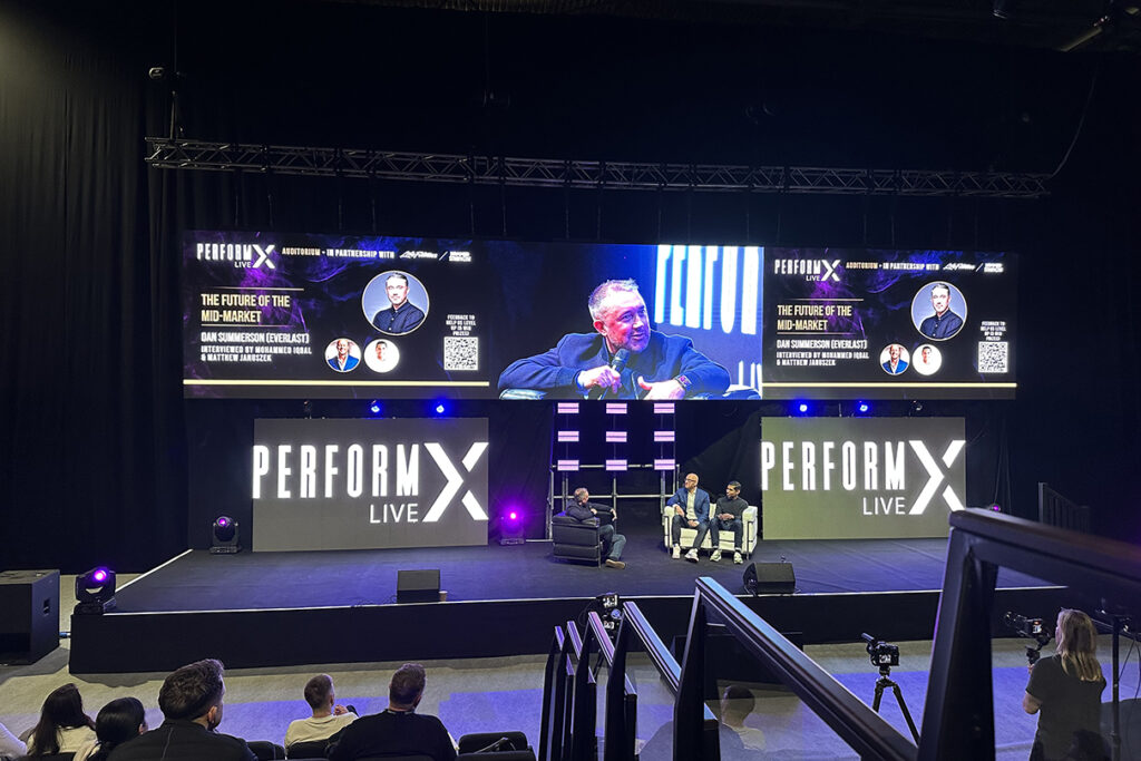 A photo from PerformX Live 2025 featuring Dan Summerson from Everlast Gyms talking on stage to the LIFTS podcast hosts